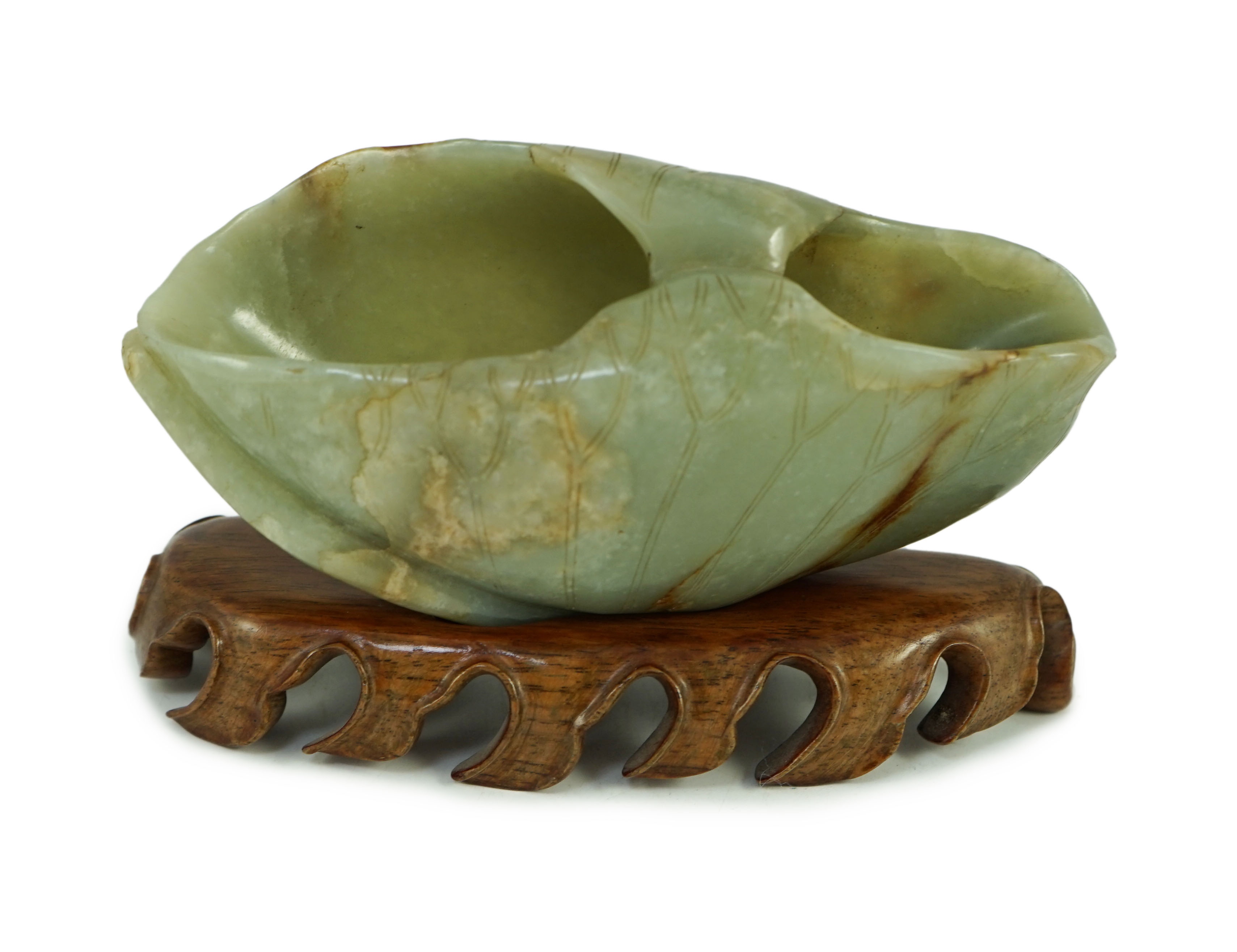 A Chinese green and russet jade ‘lotus leaf’ brushwasher, 17th/18th century, 13.5 cm across, wood stand